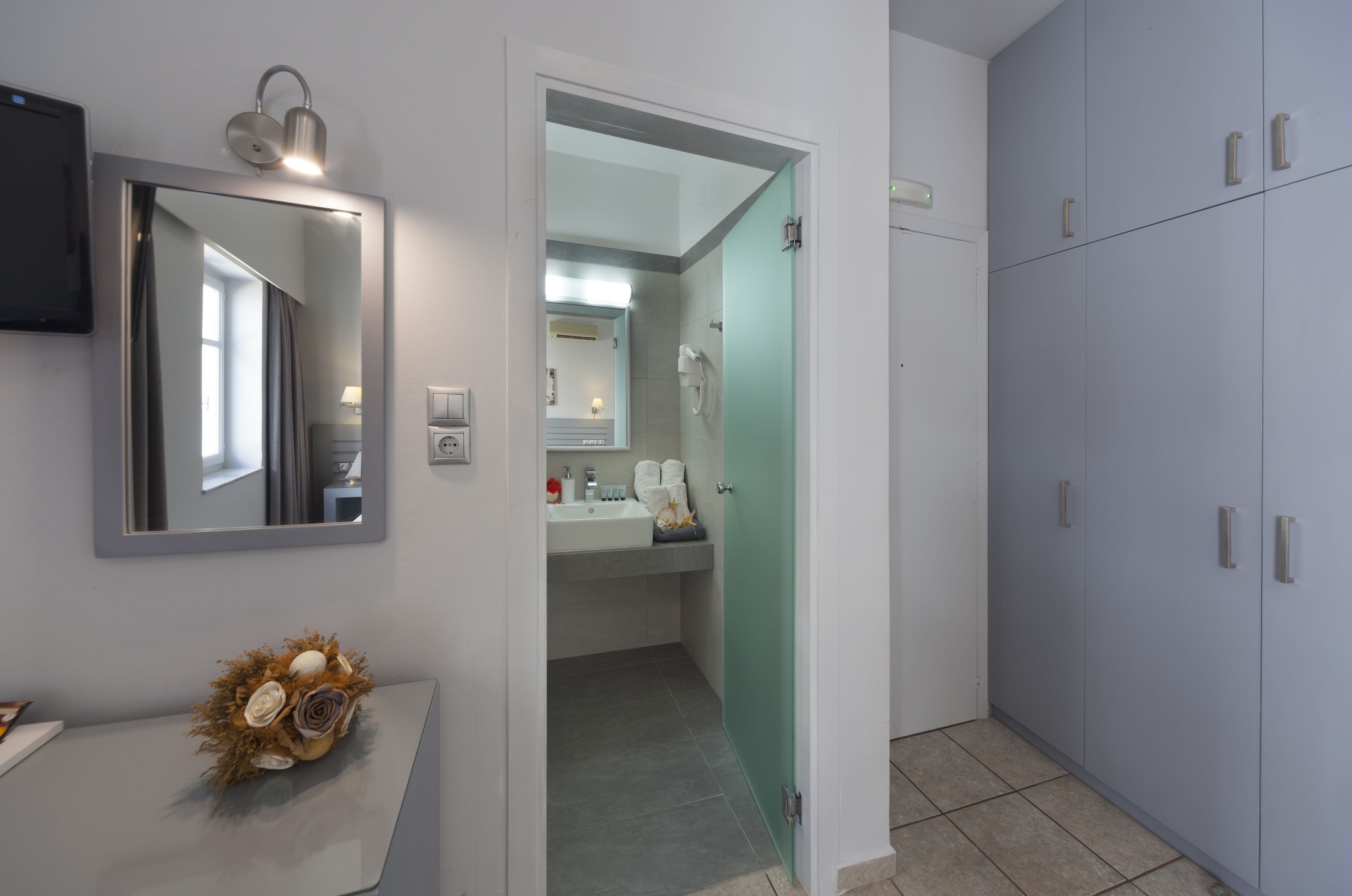Un baño moderno con espejo, lavamanos y armarios.