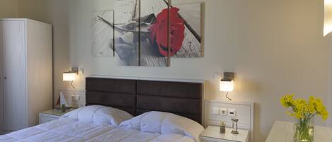 Habitación de hotel impecable con una cama grande, mesitas de noche, un armario blanco y una obra de arte colgada en la pared.