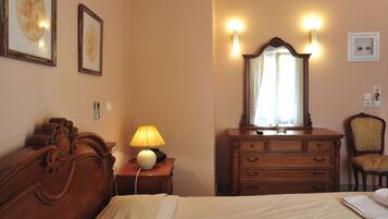 Una habitación de hotel con una cama, un aparador de madera con cajones, un espejo y luces fijadas a la pared.