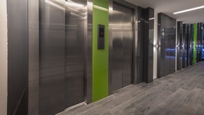 A modern elevator area with metallic doors and a green accent wall.