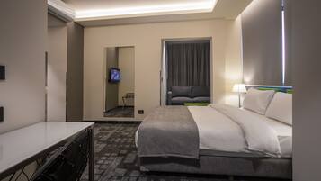A hotel room with a bed, a desk, a chair, a TV, and a window with curtains.