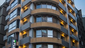 A multi-story hotel with a curved facade, balconies on each floor, and illuminated windows.