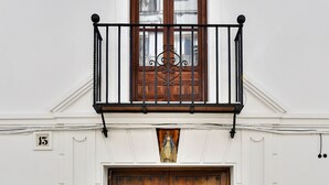 Un bâtiment doté d’une porte en bois, d’un balcon orné d’une balustrade en fer forgé et d’une petite fenêtre située au-dessus de la porte.