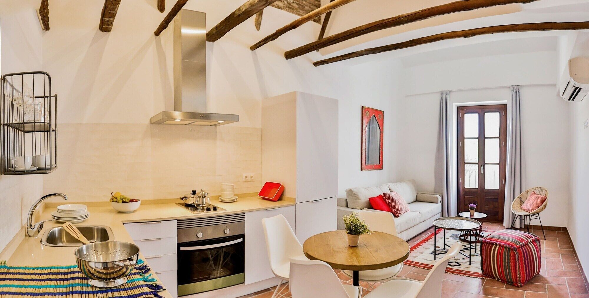 Una cuina moderna amb forns, rentapesos i zona de menjador amb taula i cadires.