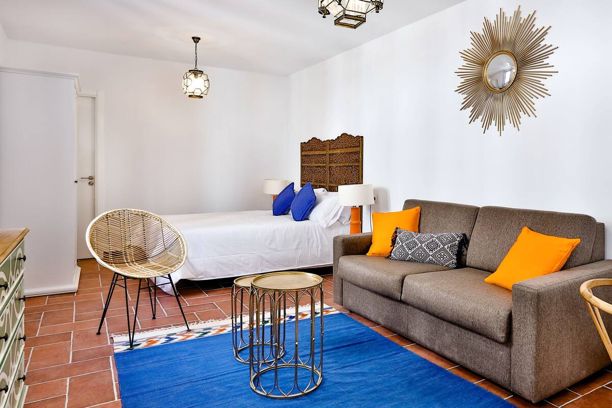 Een moderne, goed verlichte slaapkamer met een bed, een bank en een eethoek.