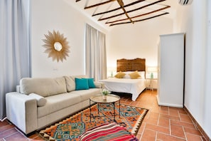 A compact living space with a sofa, a bed, a small table, and a patterned rug.