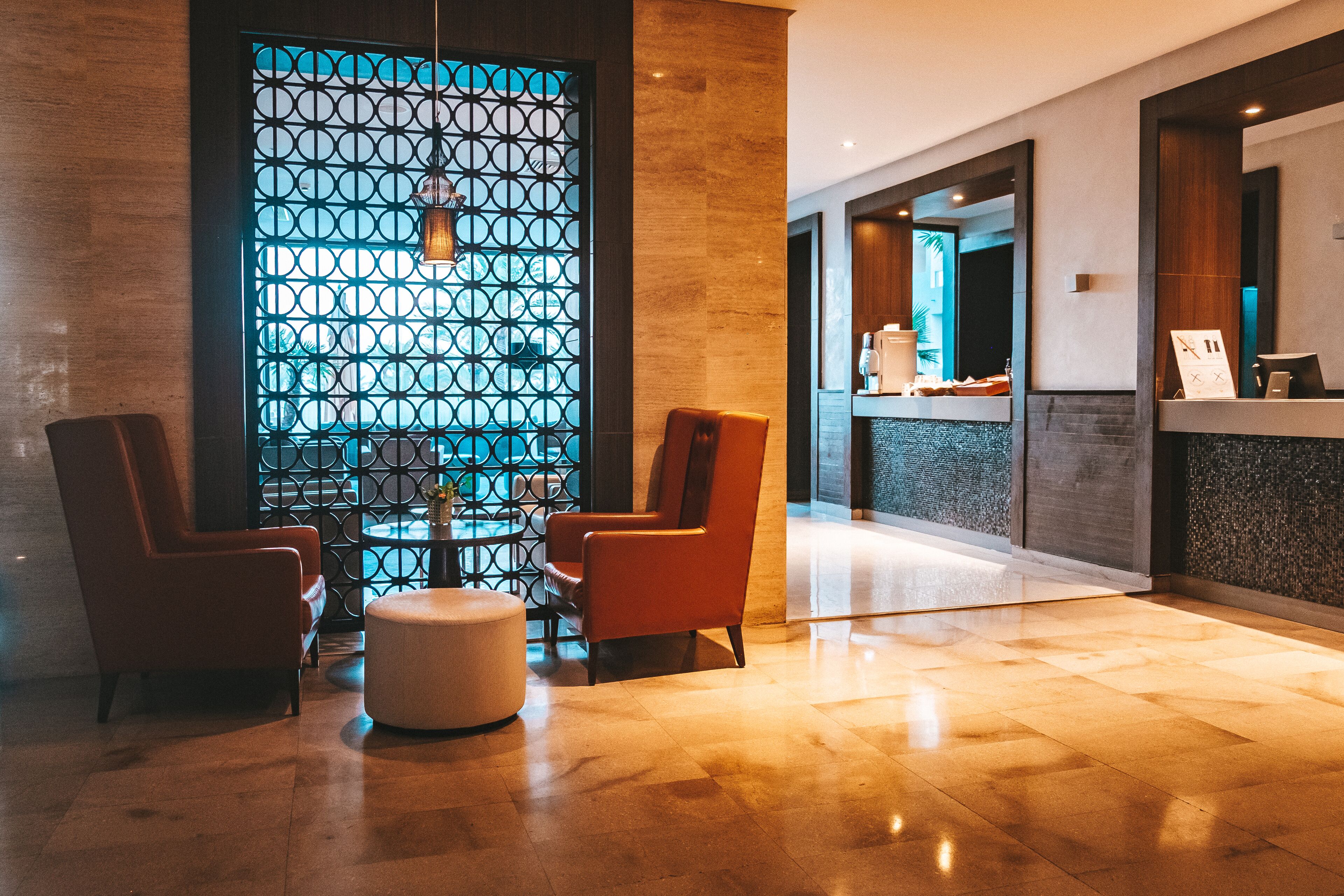 A lobby with two armchairs, a round table, and a decorative wall with a geometric pattern.