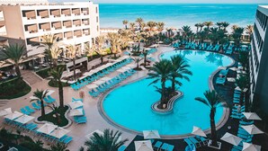 Un resort con una piscina grande, palmeras y vista al océano.