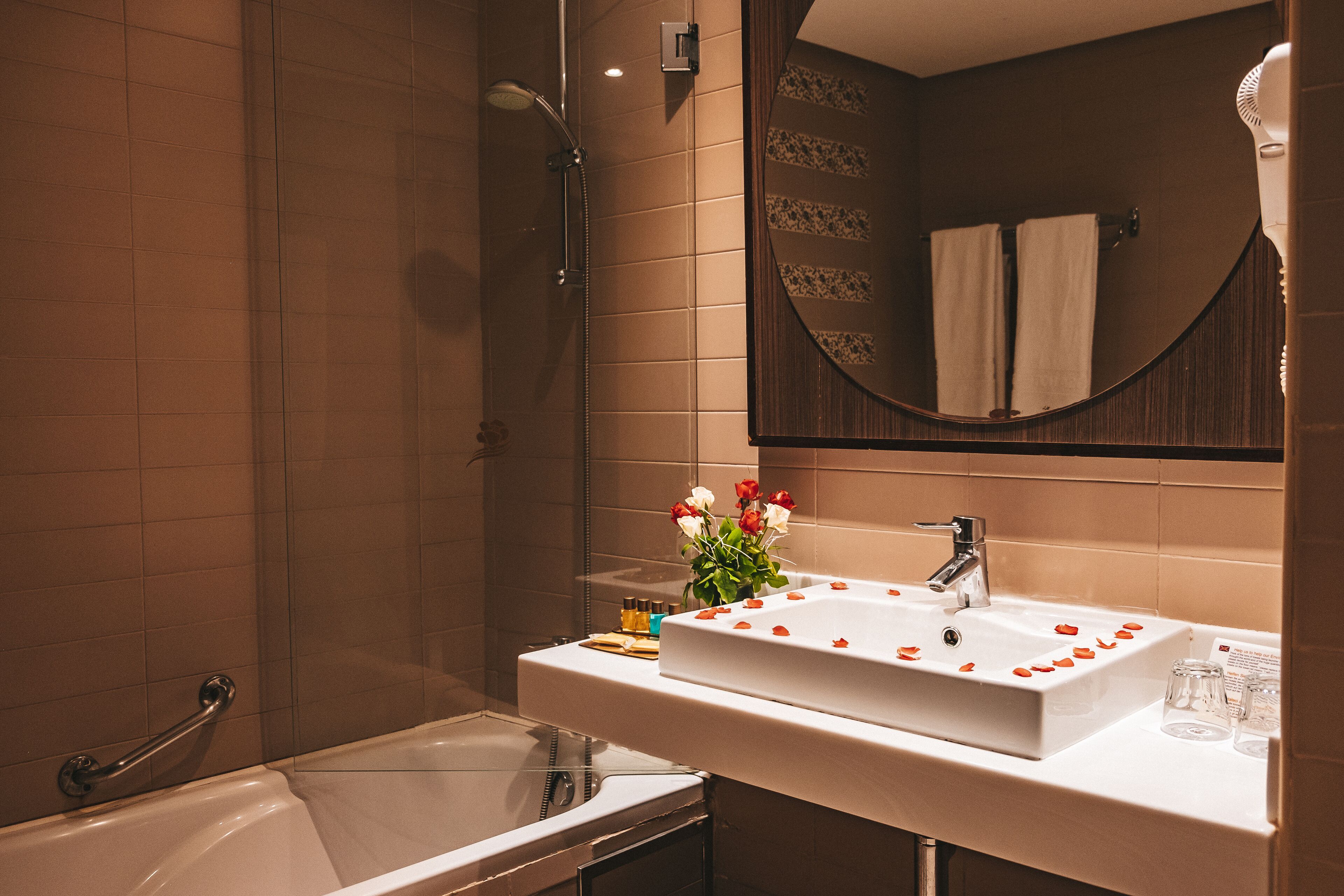 A bathroom with a white sink, a mirror, and a shower.