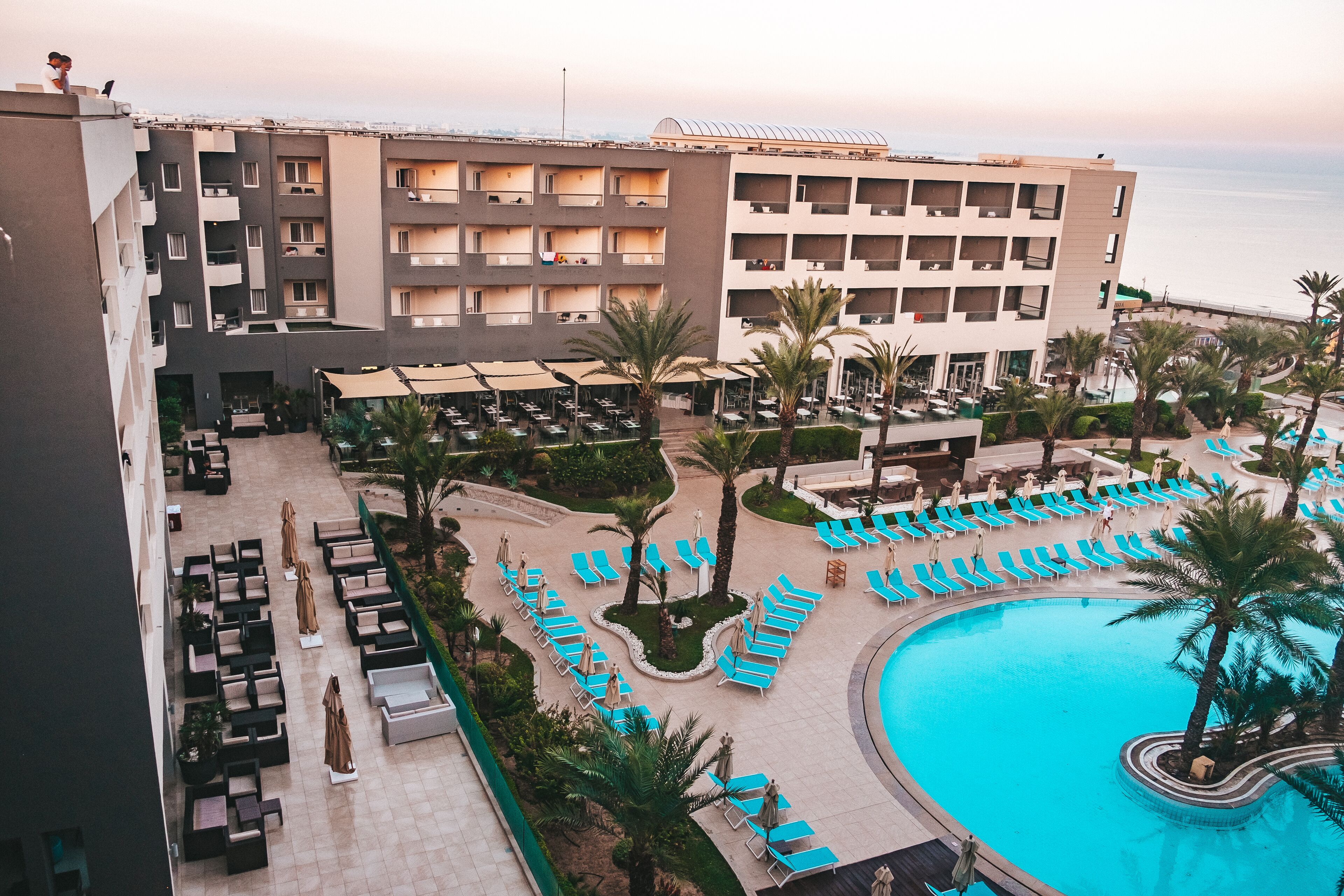Un hotel con zona de piscina, tumbonas y vista al mar.