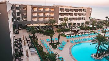 Un hotel con zona de piscina, tumbonas y vista al mar.