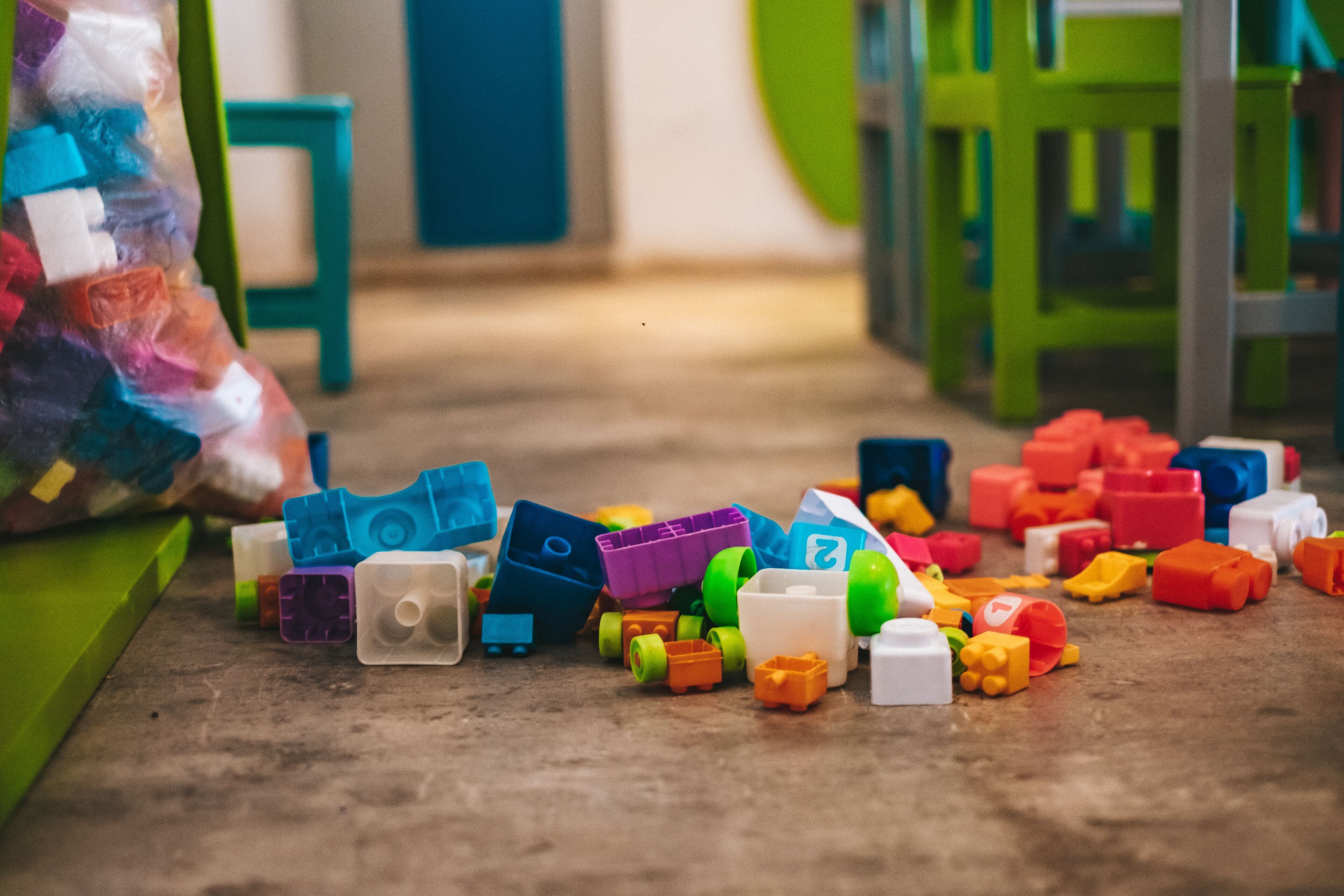 Bloques de construcción de colores variados esparcidos sobre un piso de madera.