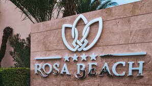 Un cartel con el nombre 'ROSA BEACH' y un logotipo encima.