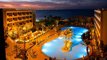 Relax by the uniquely shaped pool surrounded by palm trees and lounge chairs.