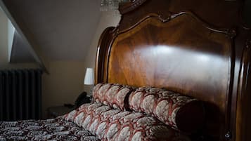 A wooden bed with a headboard, a patterned bedspread, and a lamp on a bedside table.