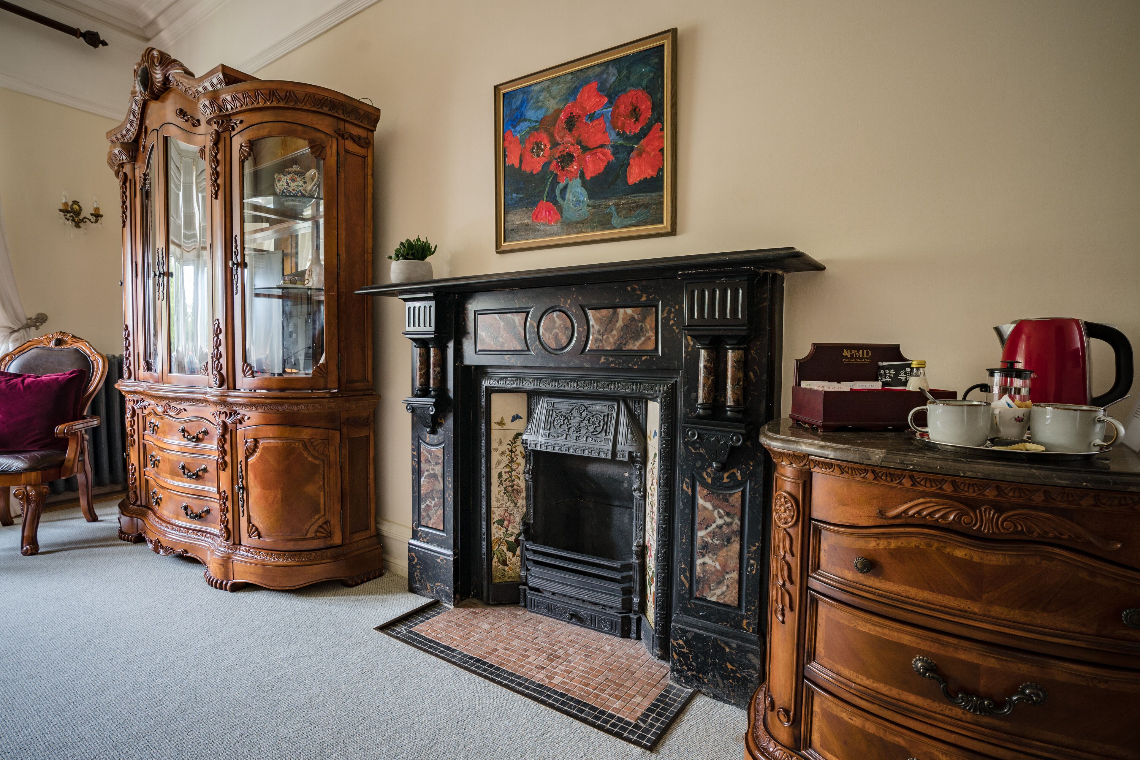 A traditional room with a fireplace, a large wooden cabinet, and a painting on the wall.