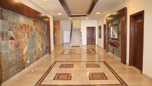Um corredor com piso de mármore, escadas e portas de madeira.