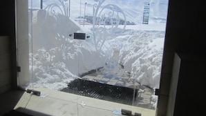 Área externa coberta de neve com uma grade de metal e detalhes decorativos em metal.