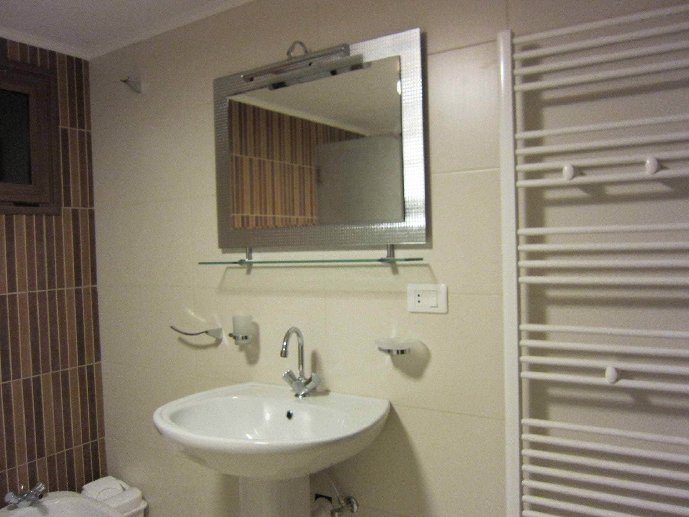 A bathroom with a white sink, a mirror, and a towel rack.