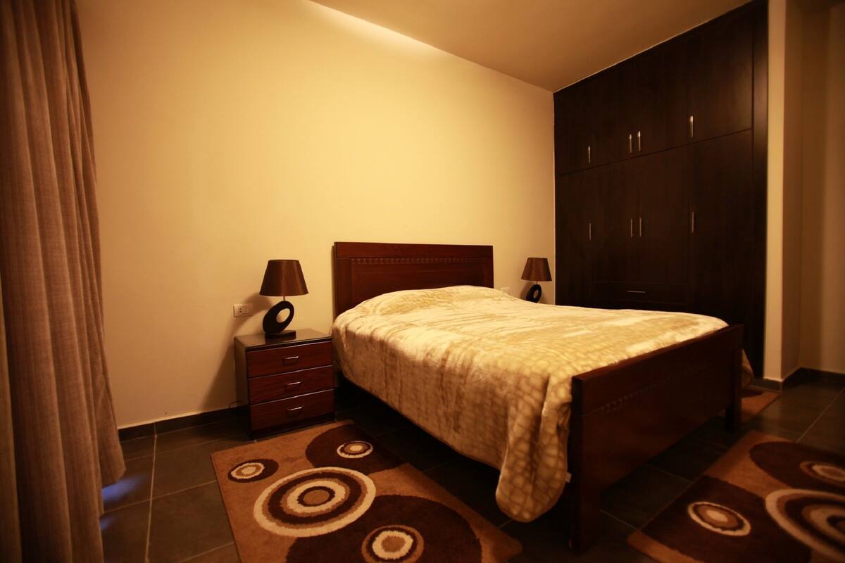 A bedroom with a bed, nightstands, a dresser, and a wardrobe.