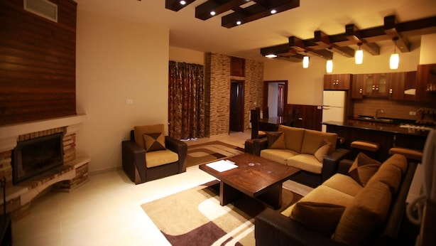 Uma sala de estar moderna com lareira, sofás, uma mesa de centro e uma área de cozinha com armários de madeira.