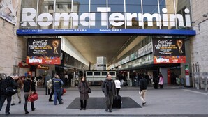 Animada entrada de estación de tren con un gran cartel que dice 'Roma Termini'.