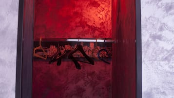 A narrow hallway with a red wall and a metal railing.