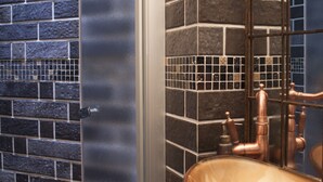 Un baño de diseño moderno con un espejo grande, un lavabo de cobre y una pared de azulejos con diseño de ladrillo.