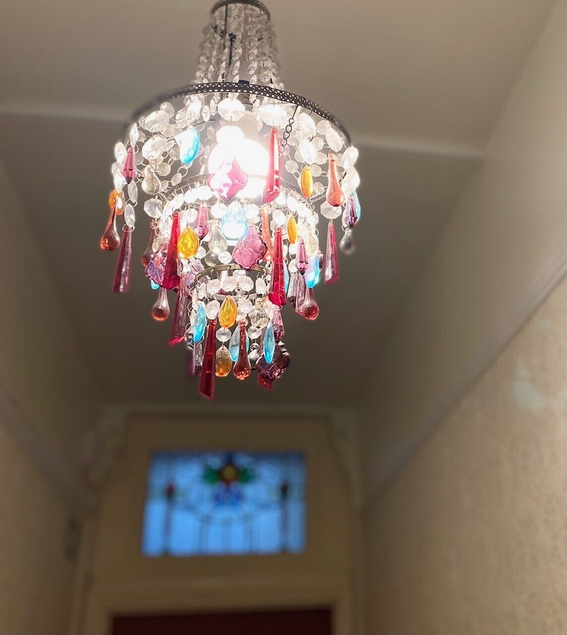 A chandelier with multiple colorful crystal pendants hanging from a metal frame.