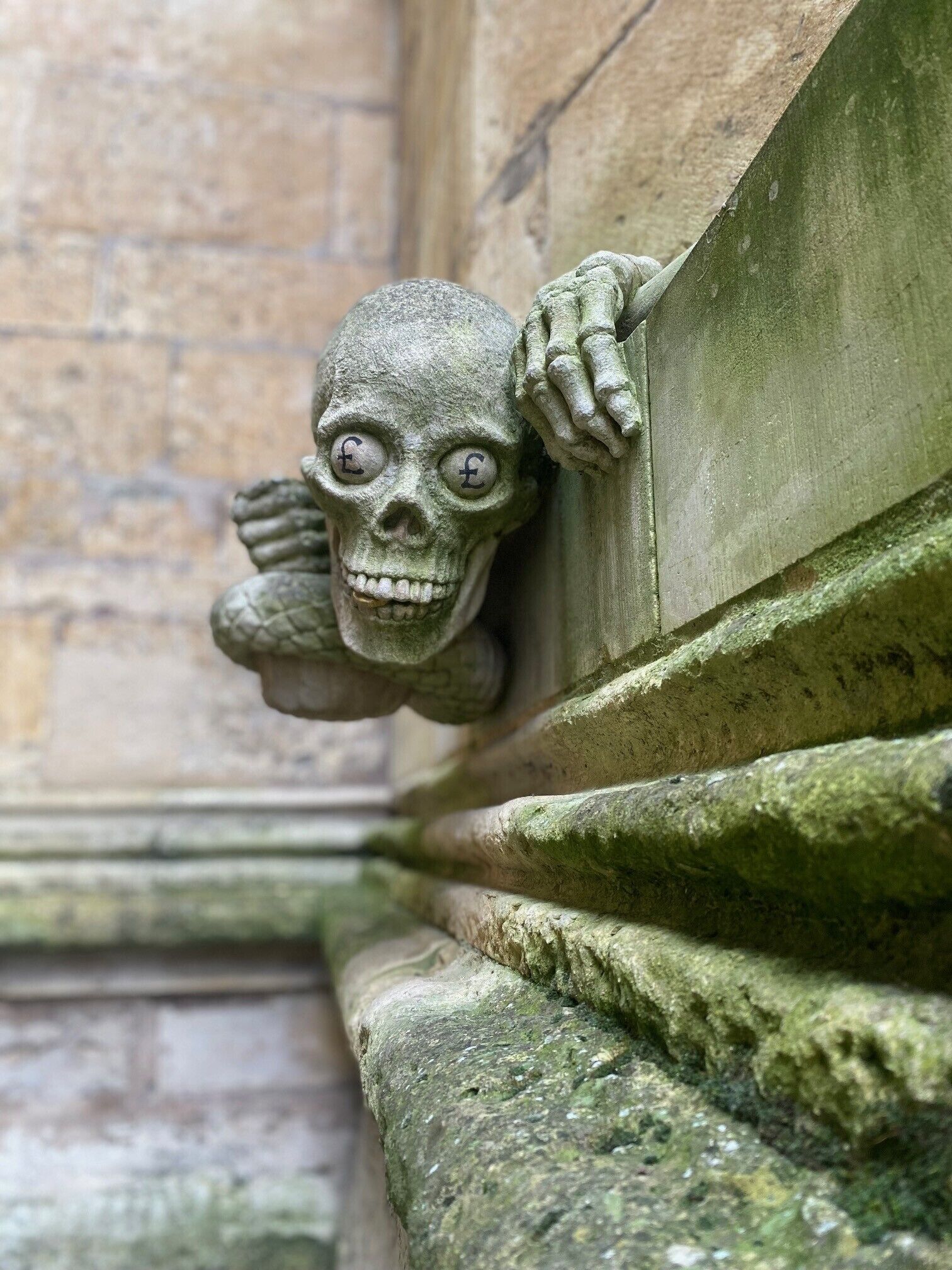 A stone gargoyle with a skull face peeking over a wall.