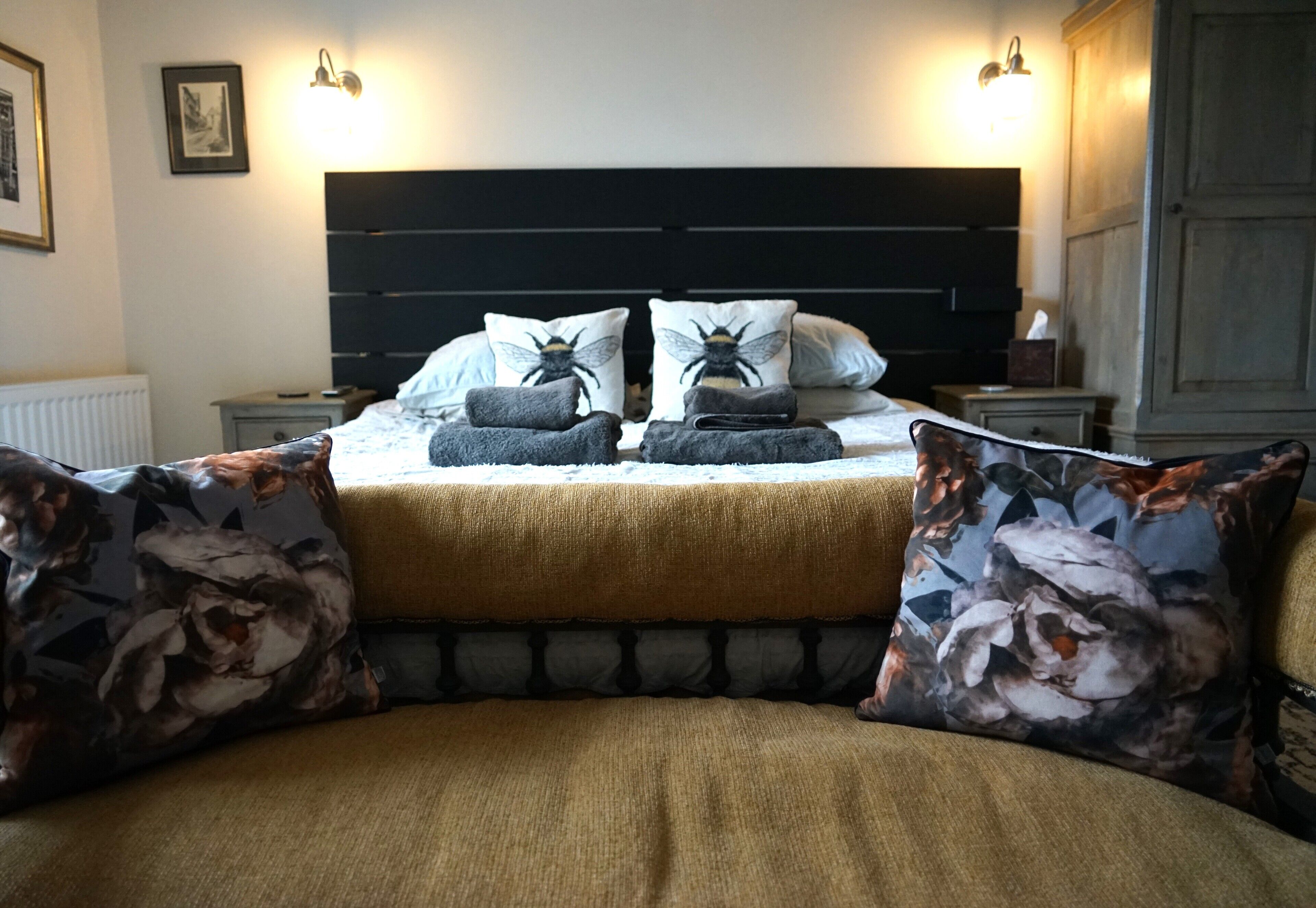 A bedroom with a bed, two nightstands, a dresser, and a large window.