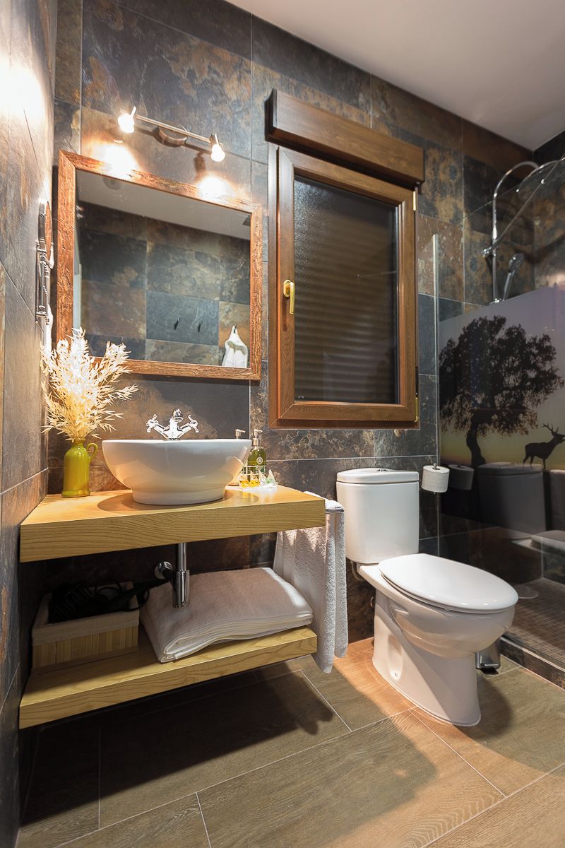 A modern bathroom with a large mirror, a vessel sink, a toilet, and a shower area.