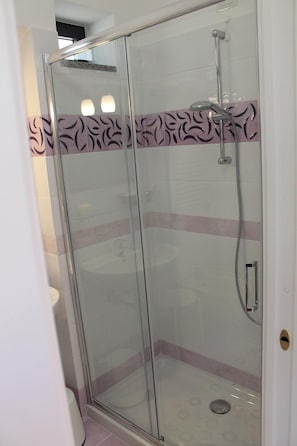 Eine Duschkabine mit Handbrause und am Wand montiertem Wasserhahn.