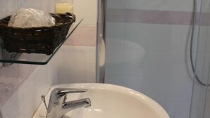 A bathroom with a white sink, a glass shower enclosure, and decorative tiles. - Gelsomino Rooms Ravello (Ravello)