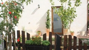 A wooden fence with potted plants and a white wall with a window. - Gelsomino Rooms Ravello (Ravello)