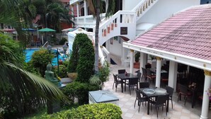 Een hotel met een zwembad, terras en een trap naar een hoger gelegen verdieping.