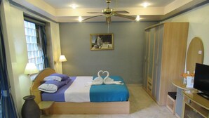Een hotelkamer met een bed, een bureau, een televisie, een garderobe en een schilderij aan de muur.