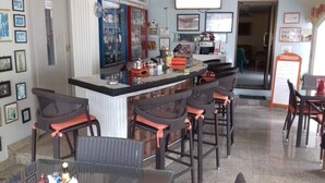 Een bar met een toonbank, barstoelen en een menubord.