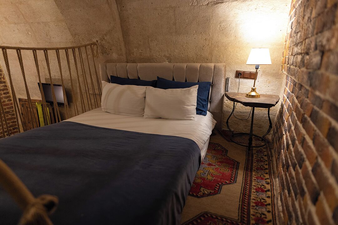 A bedroom with a bed, a nightstand, a lamp, and a patterned rug.