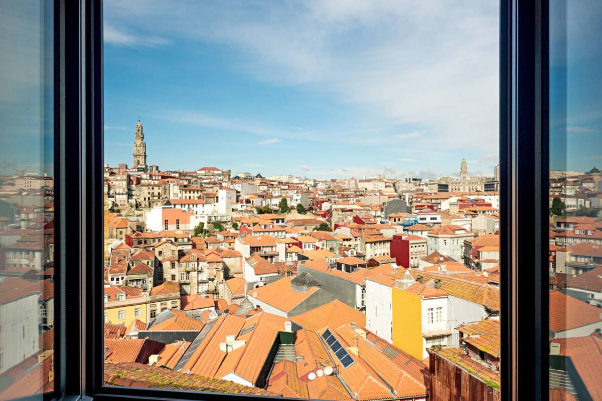 A panoramic view of a cityscape through a window, featuring a variety of buildings and a prominent tower.