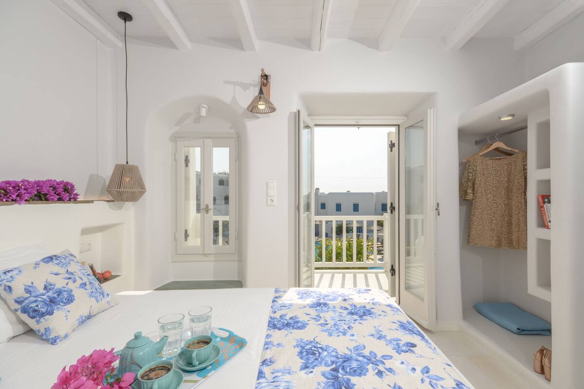 Un dormitorio con cama, mesita de noche y vistas al balcón.