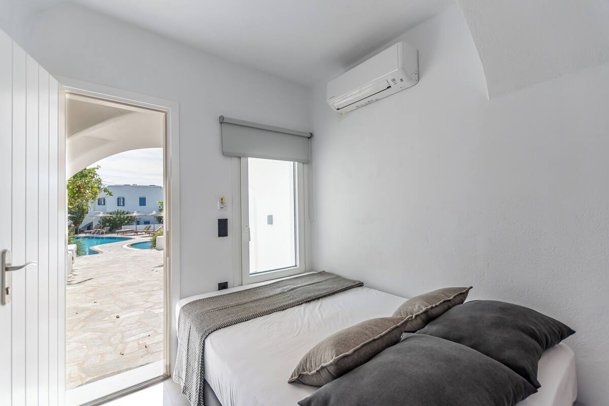 Un dormitorio con cama, ventana y aire acondicionado.