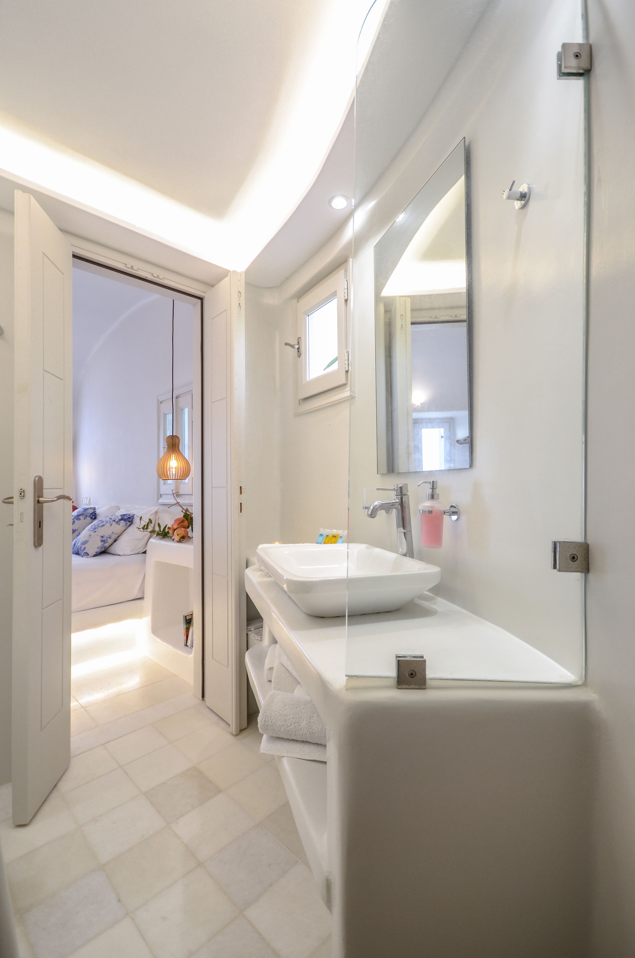 Uma casa de banho moderna com um espelho grande, lavatório branco e zona de duche.