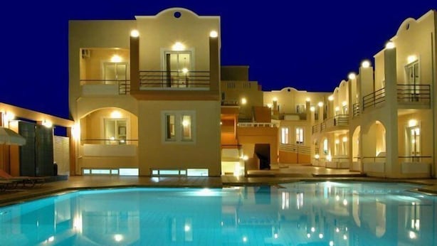 A multi-story hotel with a swimming pool, balconies, and warm lighting. - Nontas Hotel Apartaments (Chania)
