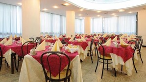 A banquet hall with round tables, chairs, and a high ceiling.