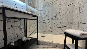 Un bagno moderno con un mobile lavabo nero, box doccia in vetro e pareti a effetto marmo.