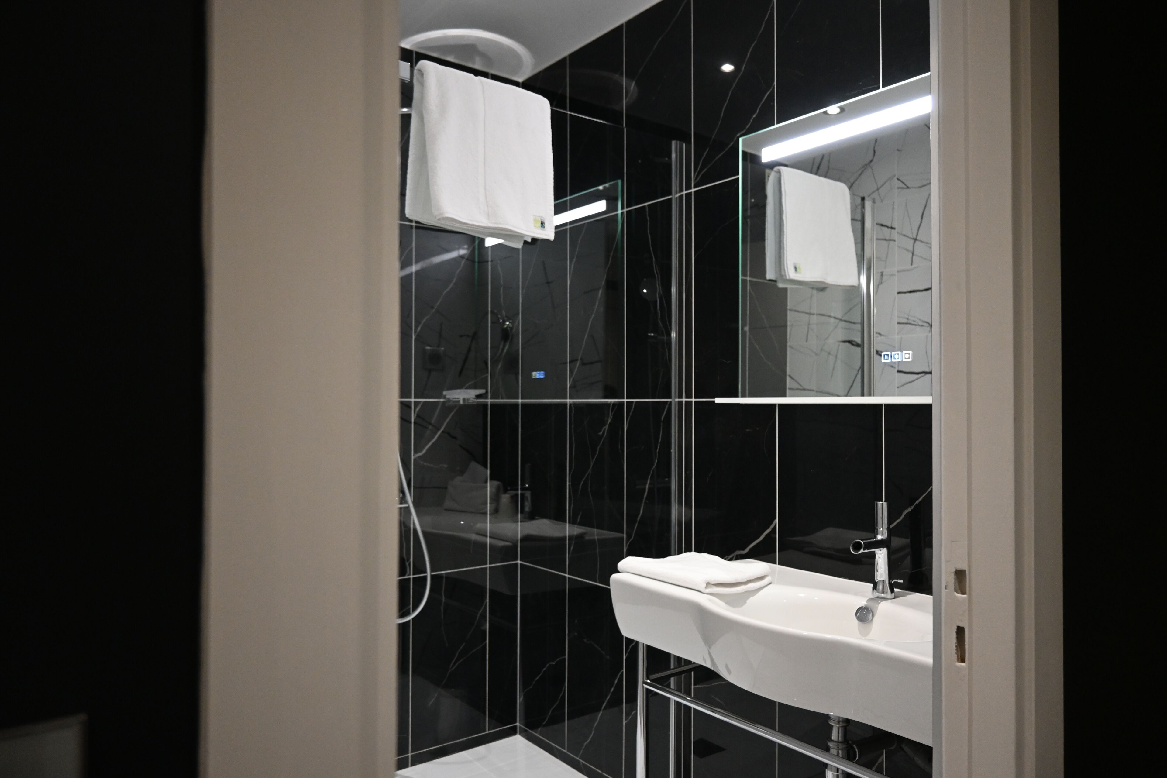 A modern bathroom with a white sink, a mirror, and a towel hanging on a rack.