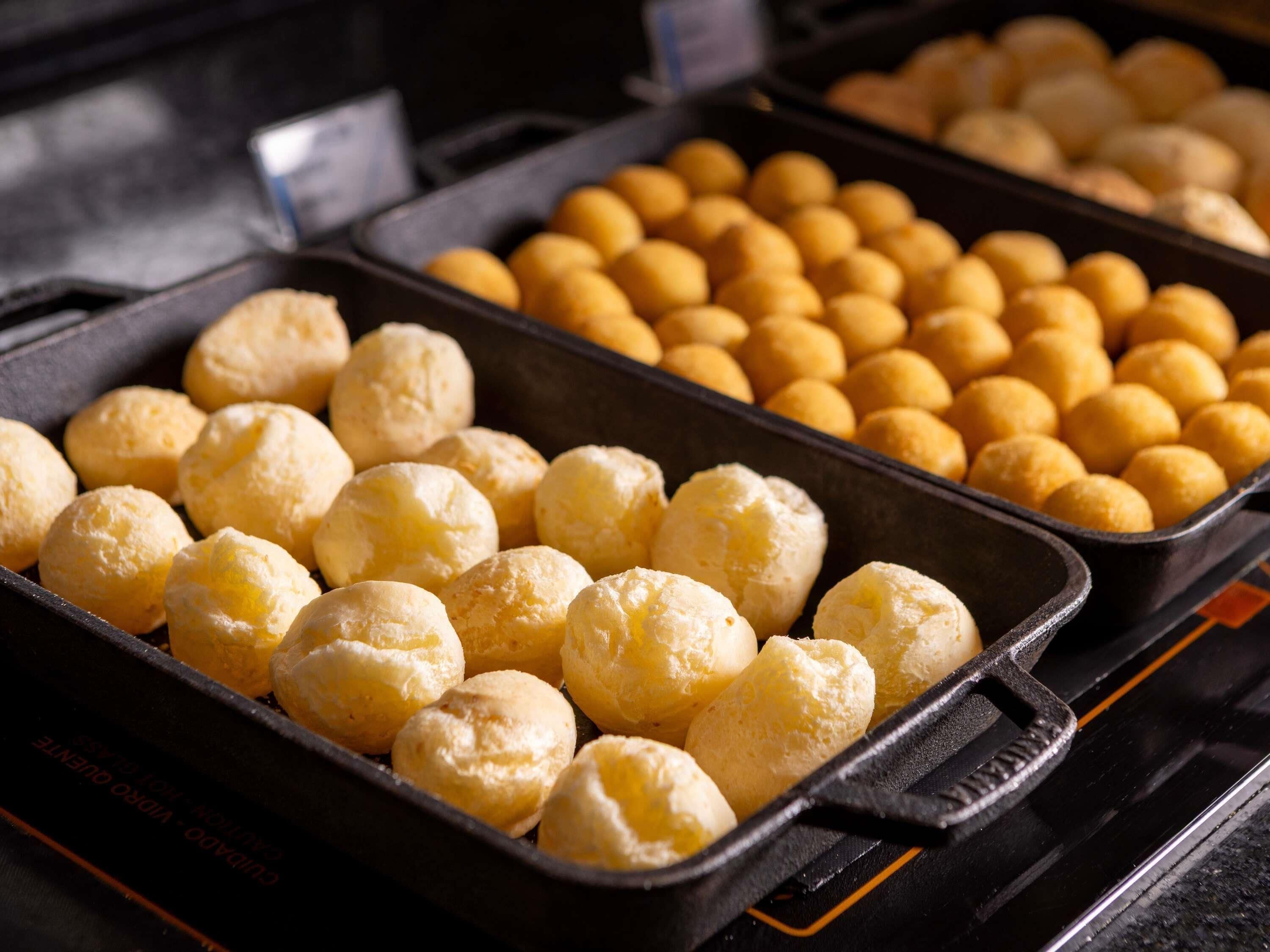 A tray of golden-brown pastries, likely a type of bread or pastry, in a commercial setting.