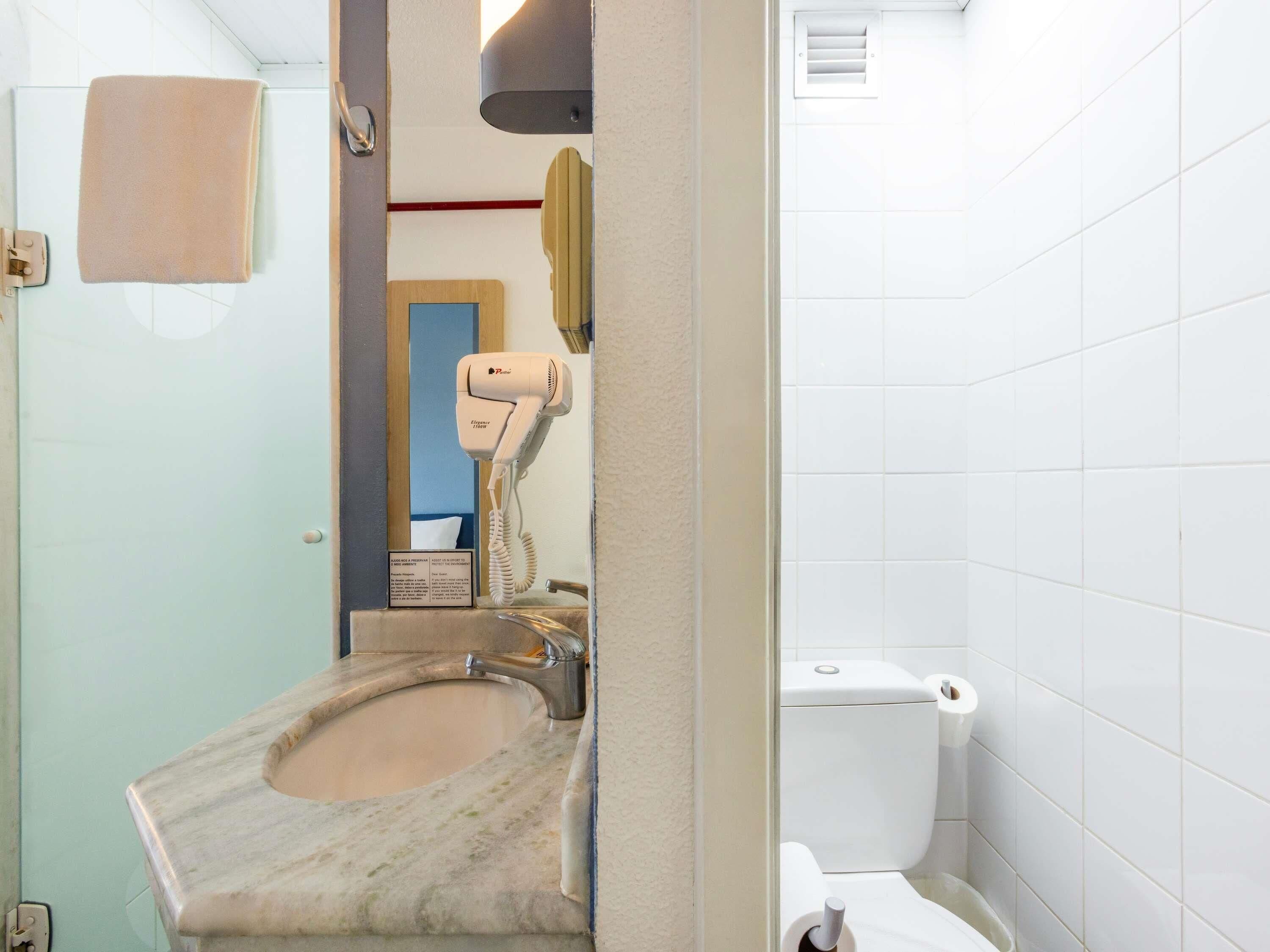 Ein Badezimmer mit Marmorwaschbecken, Fön, Toilette und Handtuchhalter.