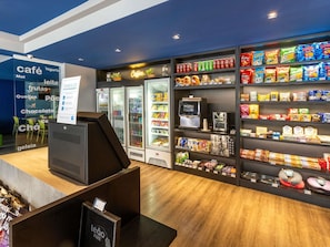Un café doté d’un comptoir en libre-service, de boissons réfrigérées et d’étagères remplies de collations et de boissons.